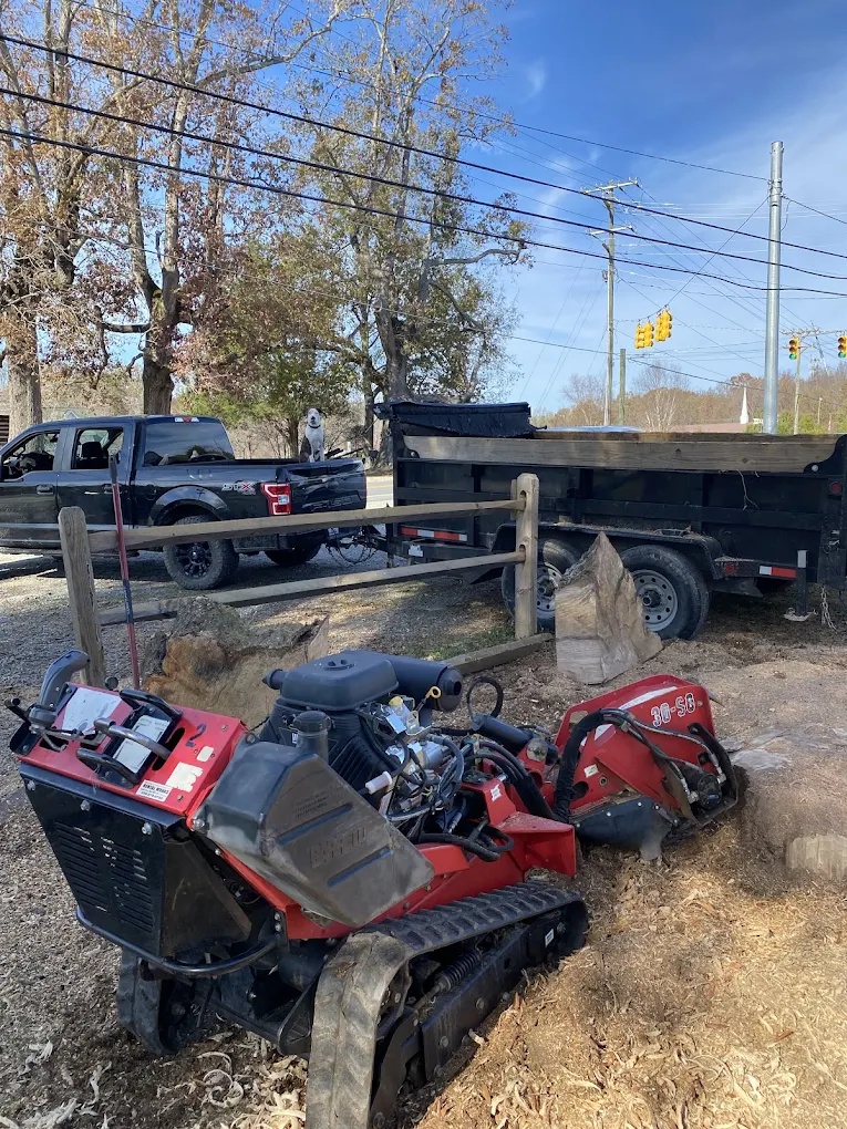 Stump grinding machine and hauling trailer staged for a tree service job in High Point, NC